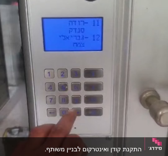 אדם לוחץ על כפתור במערכת אינטרקום עם מסך תצוגה